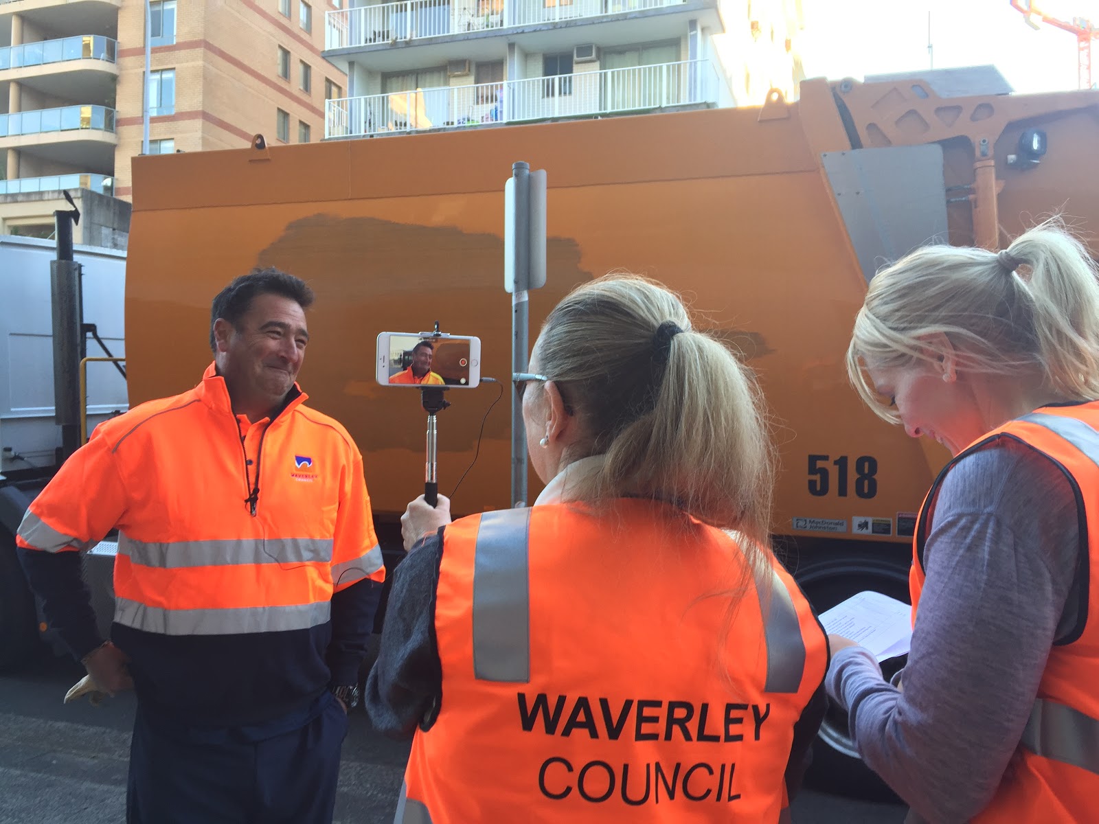 Two staff members from Waverley Council, holding a smartphone and interviewing a garbage man.